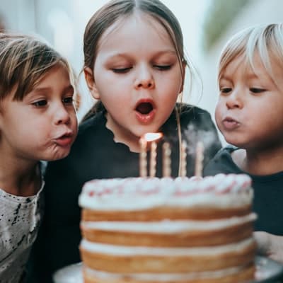 Doğum günü pastasındaki mumları üfleyen çocuklar